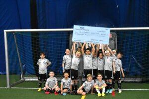 Tri City Soccer team holding a check